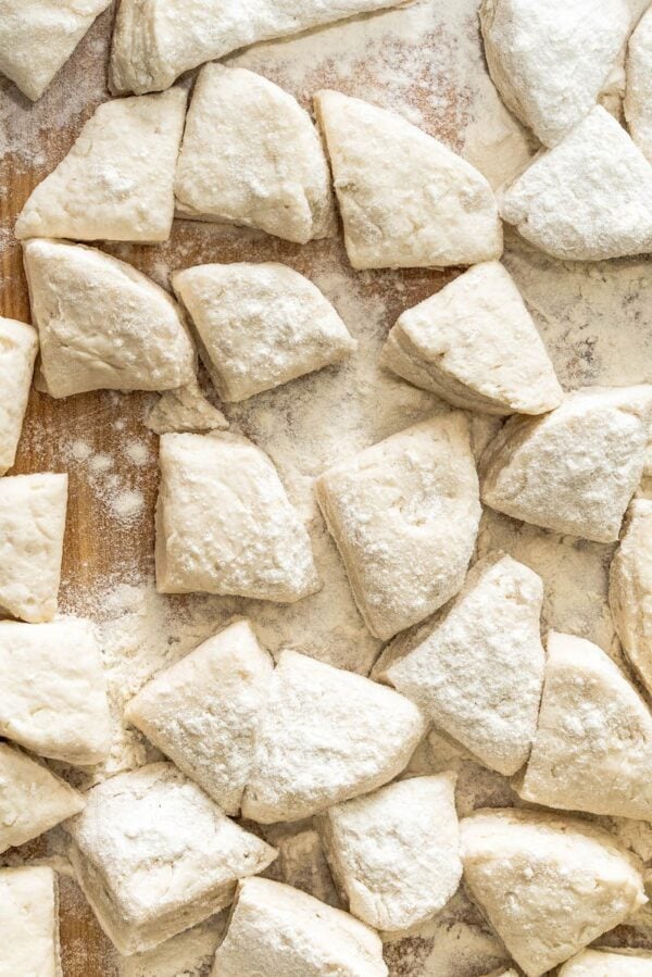 Canned biscuits on a cutting board cut into quarters.