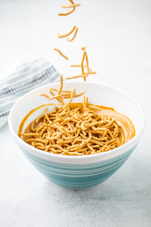 Crispy noodles falling into a mixing bowl.