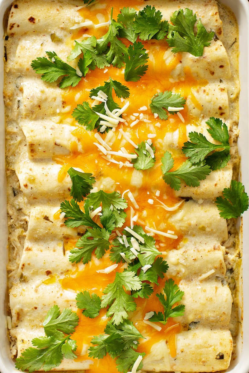 Sour cream chicken enchiladas with cheese and cilantro on top.