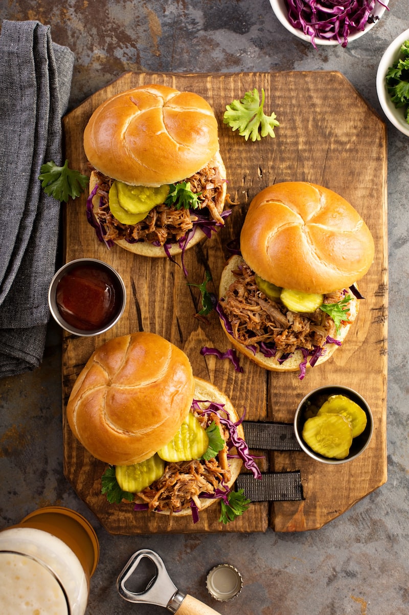 Pulled pork crockpot sandwiches on a chopping board.