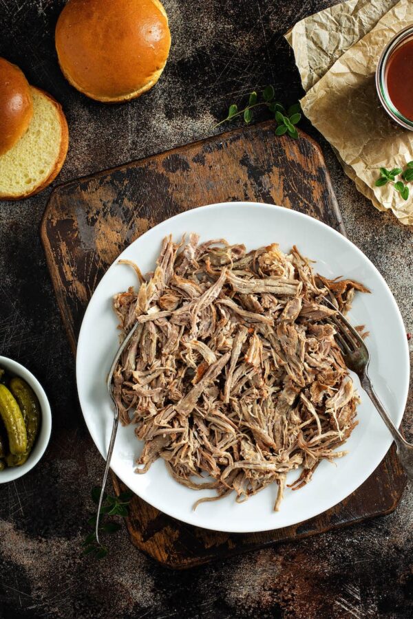 Pulled pork from crockpot shredded on a white plate.