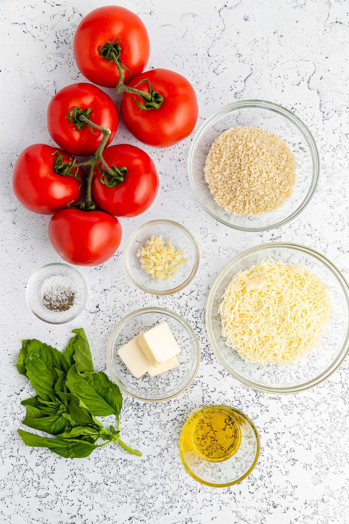 From top left: Vine-ripe tomatoes, bread crumbs, salt and pepper, garlic, cheese, fresh basil, butter, olive oil.