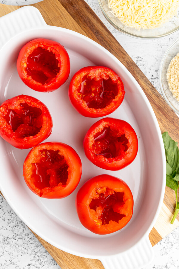 Cored tomatoes in a baking dish.