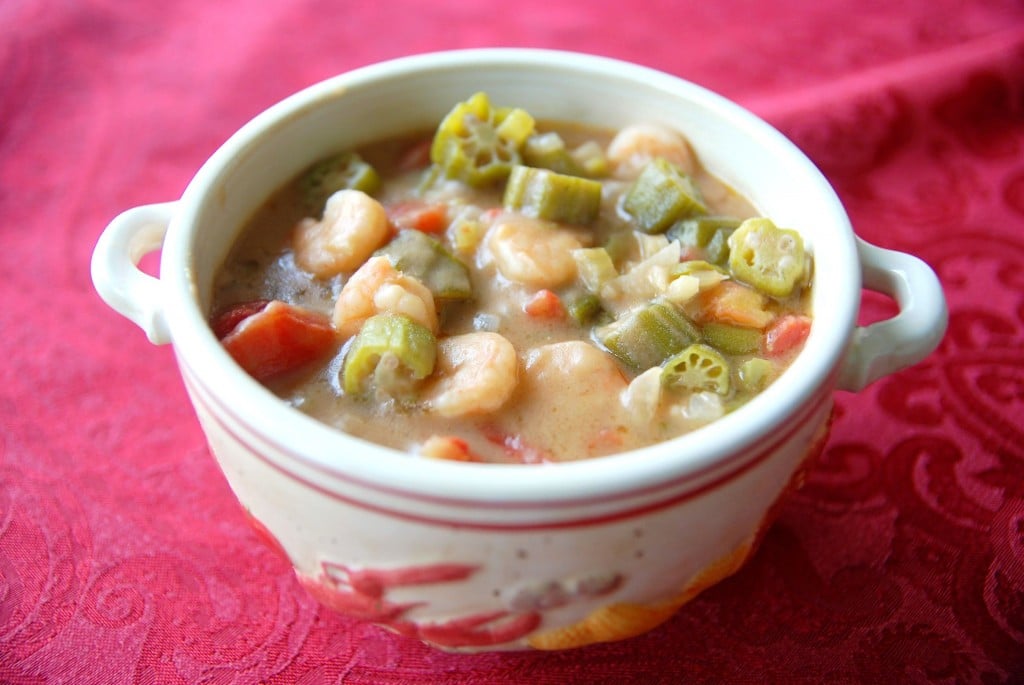 A white bowl with handles is filled with seafood gumbo