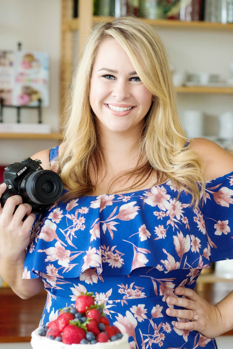 Jessica Segarra in a Blue Floral Dress Holding a Digital Camera