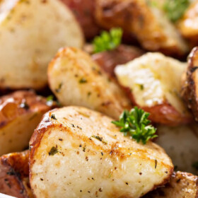 Close up image of roasted potatoes on a plate with herbs.