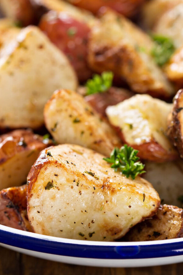 Close up image of roasted potatoes on a plate with herbs.
