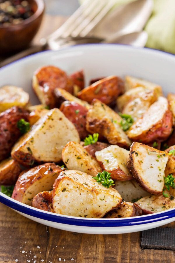 Up close image of oven roasted potatoes in a white bowl.