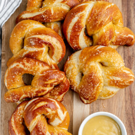Overhead shot of baked goods on a cutting board, with a cup of creamy dipping sauce.