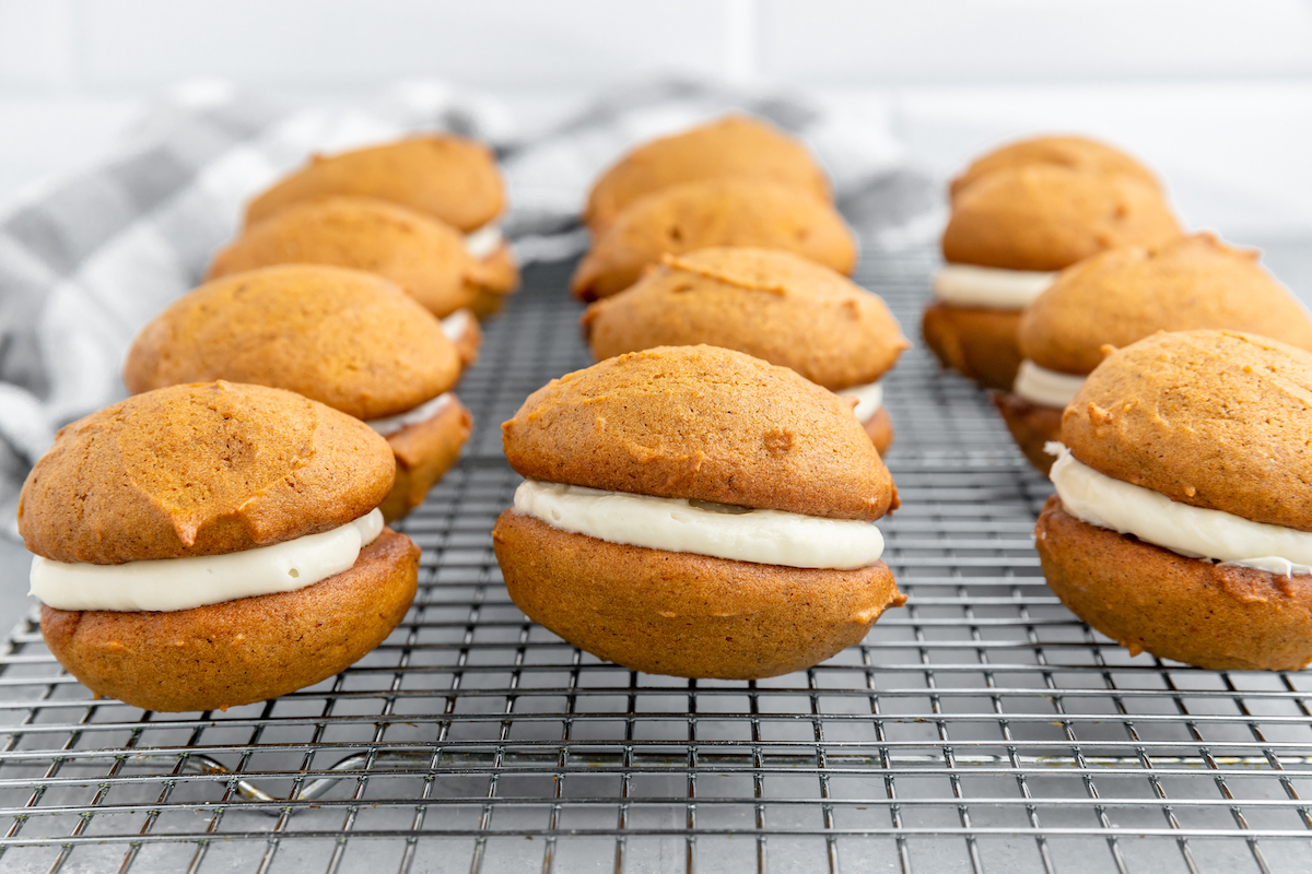 Pumpkin sandwich cookie desserts on a cooling rack.