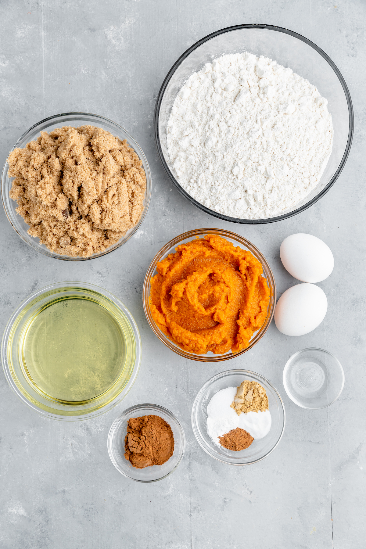 From top left: Brown sugar, flour, oil, pumpkin, eggs, cinnamon, baking powder, baking soda, spices, vanilla.