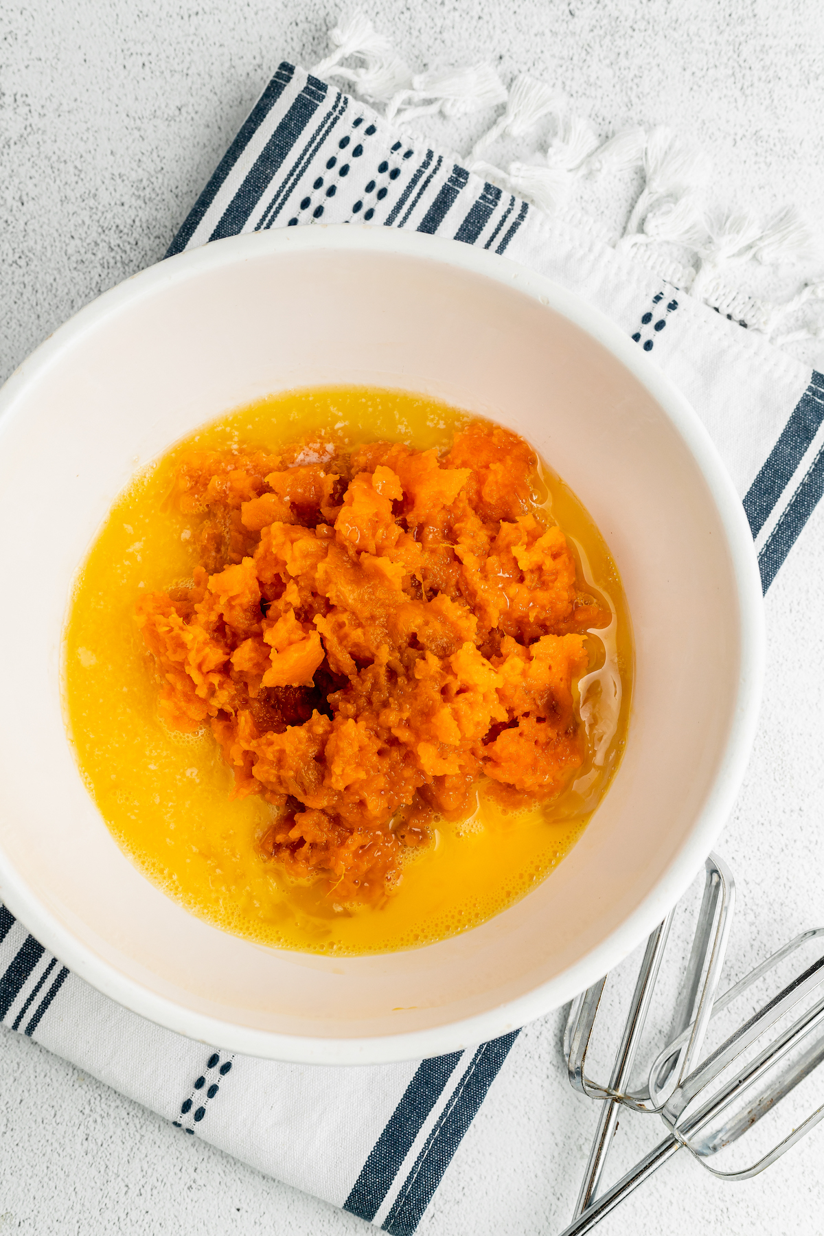Sweet potato puree, melted butter, and eggs in a mixing bowl.