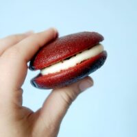 a hand holding a red velvet whoopie pie
