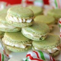 Green pistachio macarons stacked on top of each other with red and green ribbon