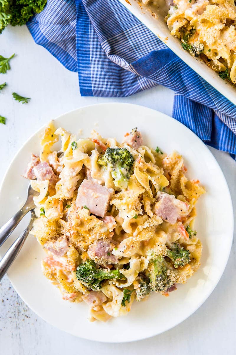 A bowl of ham casserole with broccoli, carrots, and creamy cheese sauce. 