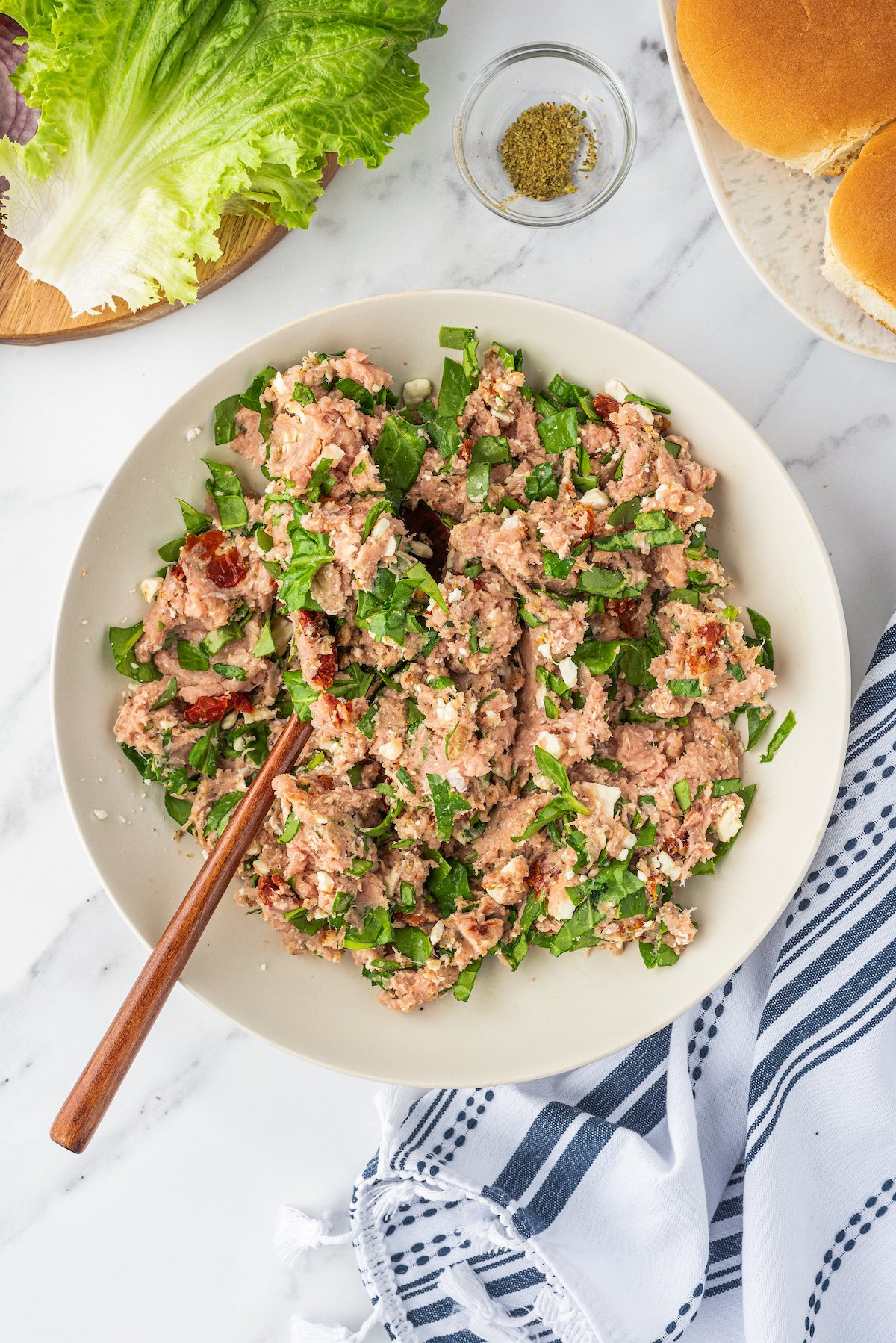 Ground turkey mixed with chopped spinach and other ingredients in a large bowl.