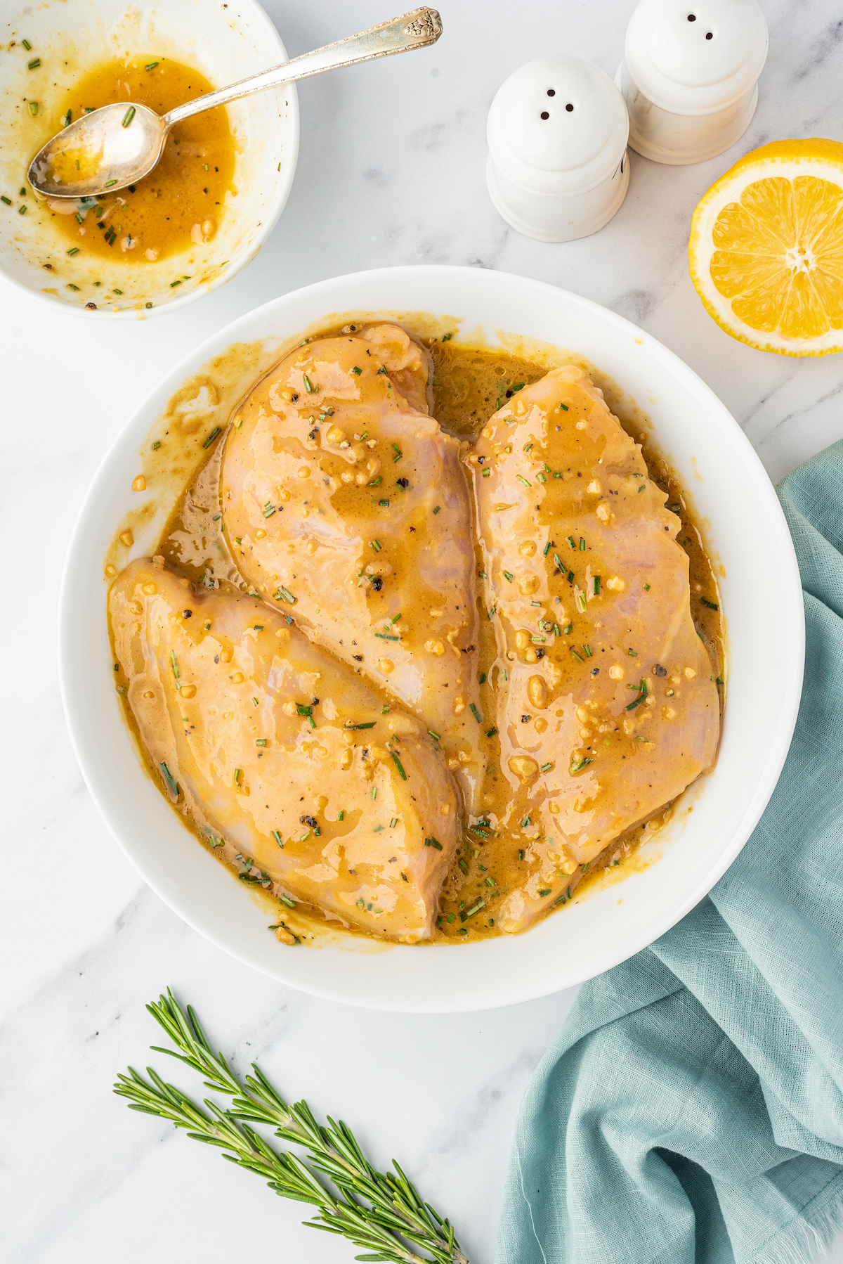 Chicken marinating in a shallow, white bowl.