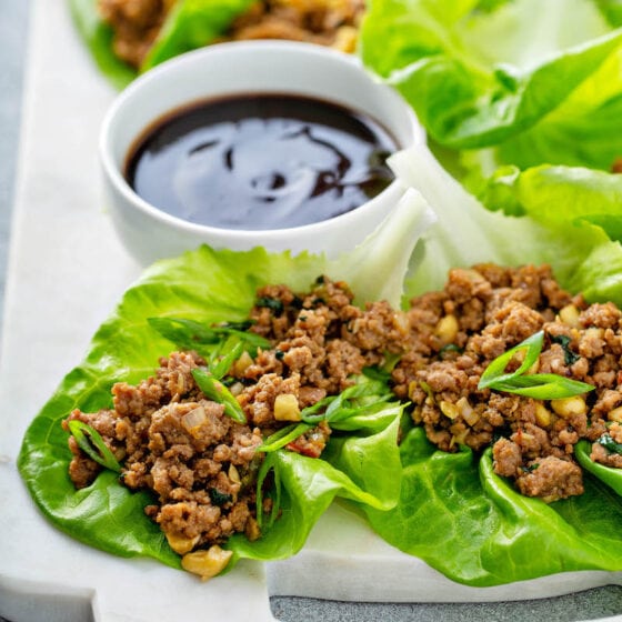 Lettuce wraps being served on a platter with dipping sauce.