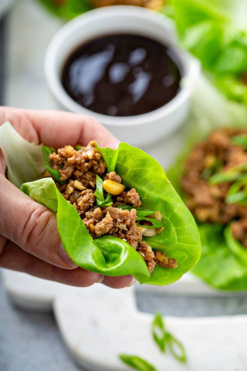 Lettuce wraps in a hand about to be eaten. 