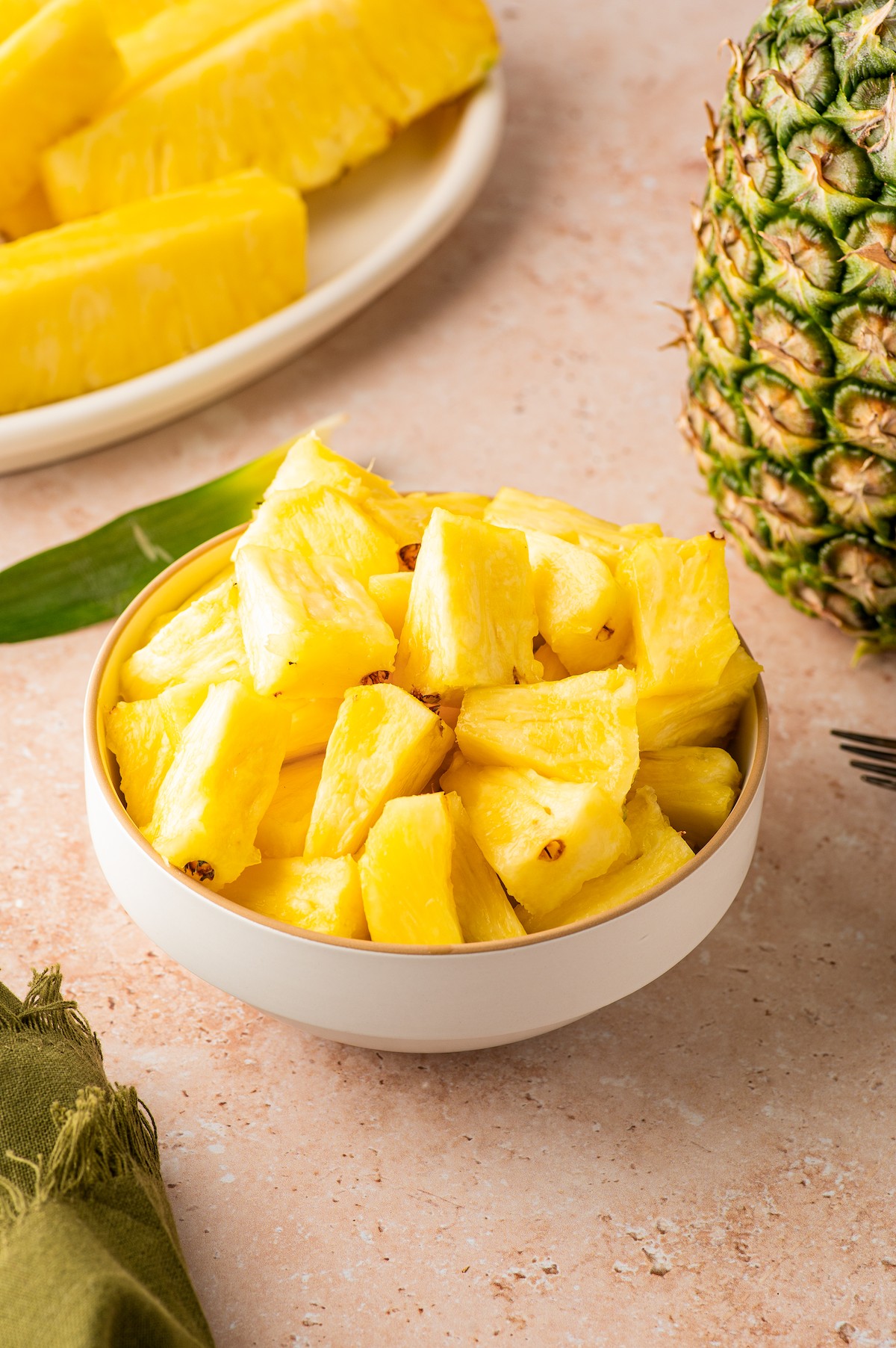 Bite-sized pieces of pineapple in a white bowl.