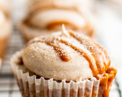 A frosted cupcake, drizzled with dulce de leche and cinnamon sugar.
