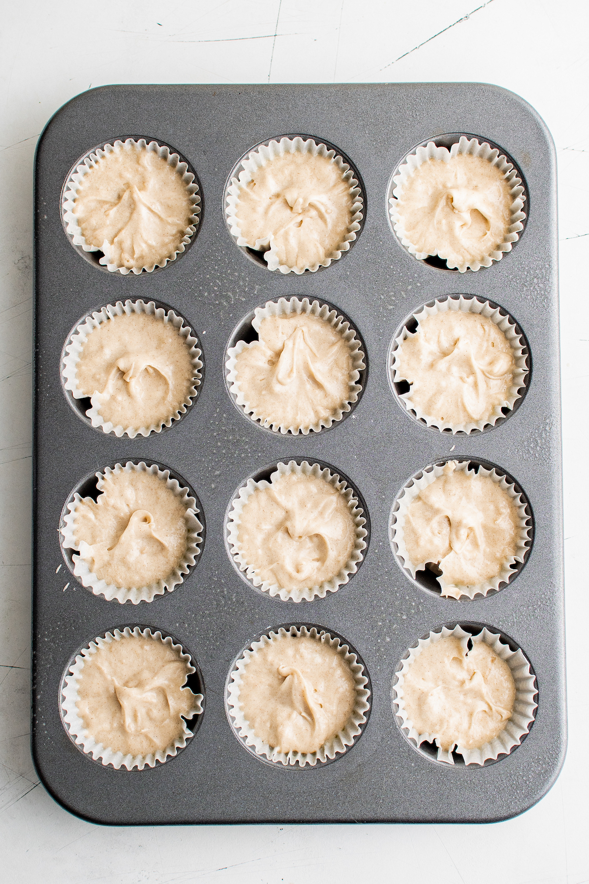 Unbaked cupcake batter, in a muffin tin lined with cupcake liners.
