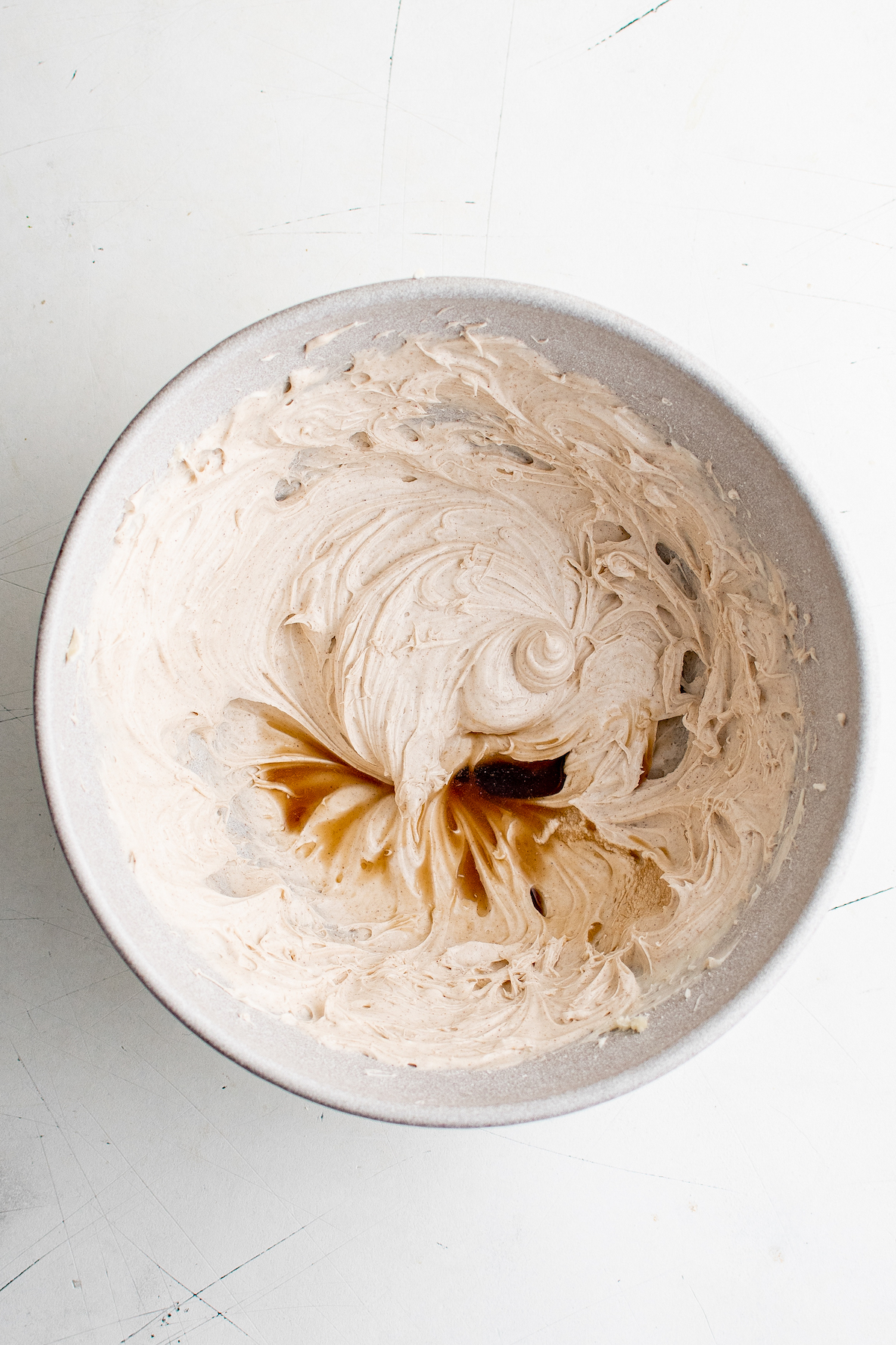 Cream cheese frosting in a mixing bowl, with vanilla extract poured in.