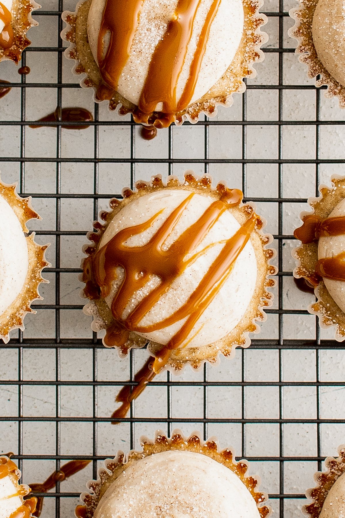 Frosted cupcakes on a cooling rack, drizzled with dulce de leche.