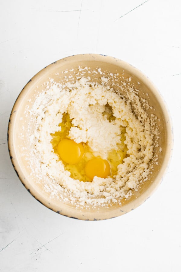 Creamed butter and sugar in a mixing bowl, with an egg cracked into the bowl as well.