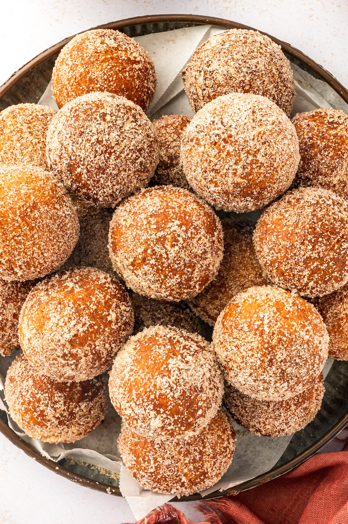 A serving plate filled with homemade donut holes tossed in sweet cinnamon sugar.