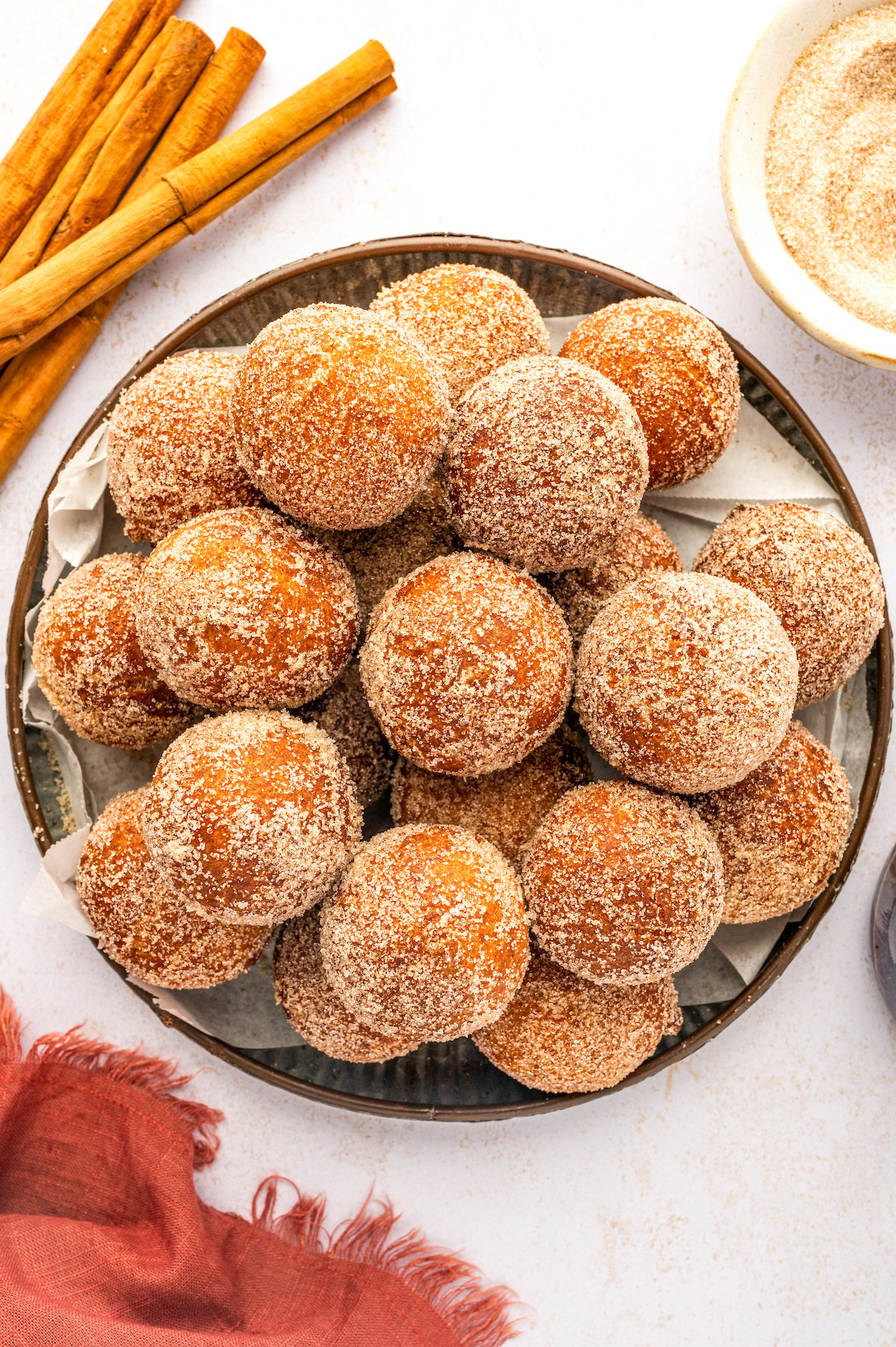 Homemade donut holes tossed in cinnamon sugar on a plate. 