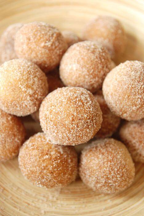 A close-up of donut holes covered in cinnamon sugar on a yellow plate