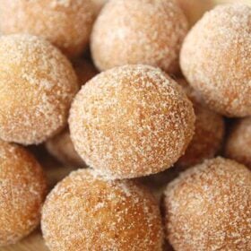 Close up of donut holes covered in cinnamon sugar on a yellow plate