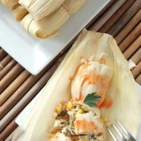 Overhead image of wrapped tamales and one tamale unwrapped.