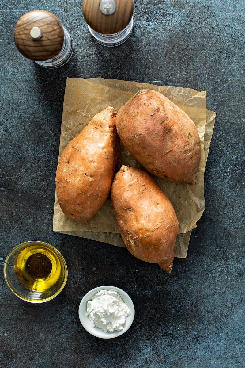 Sweet potatoes on parchment paper with oil, cornstarch, salt and pepper.