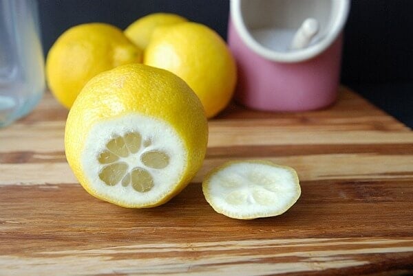 A lemon on its side with the end cut off and laying next to it