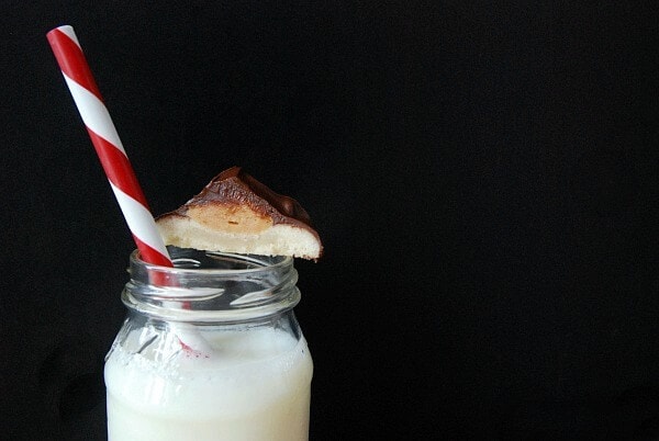 Half of a Tagalongs Cookie Balanced on the Rim of a Glass of Milk