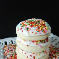 Four sugar cookies stacked on top of each other with sprinkles.