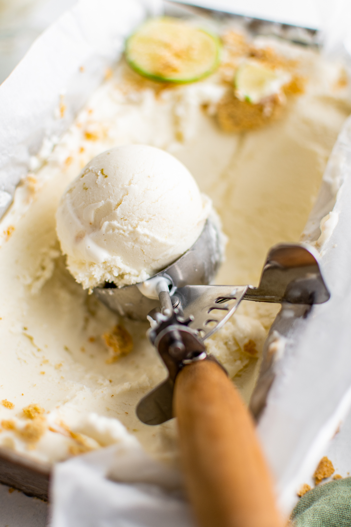 Frozen yogurt being scooped from a small dish with an ice cream scoop.