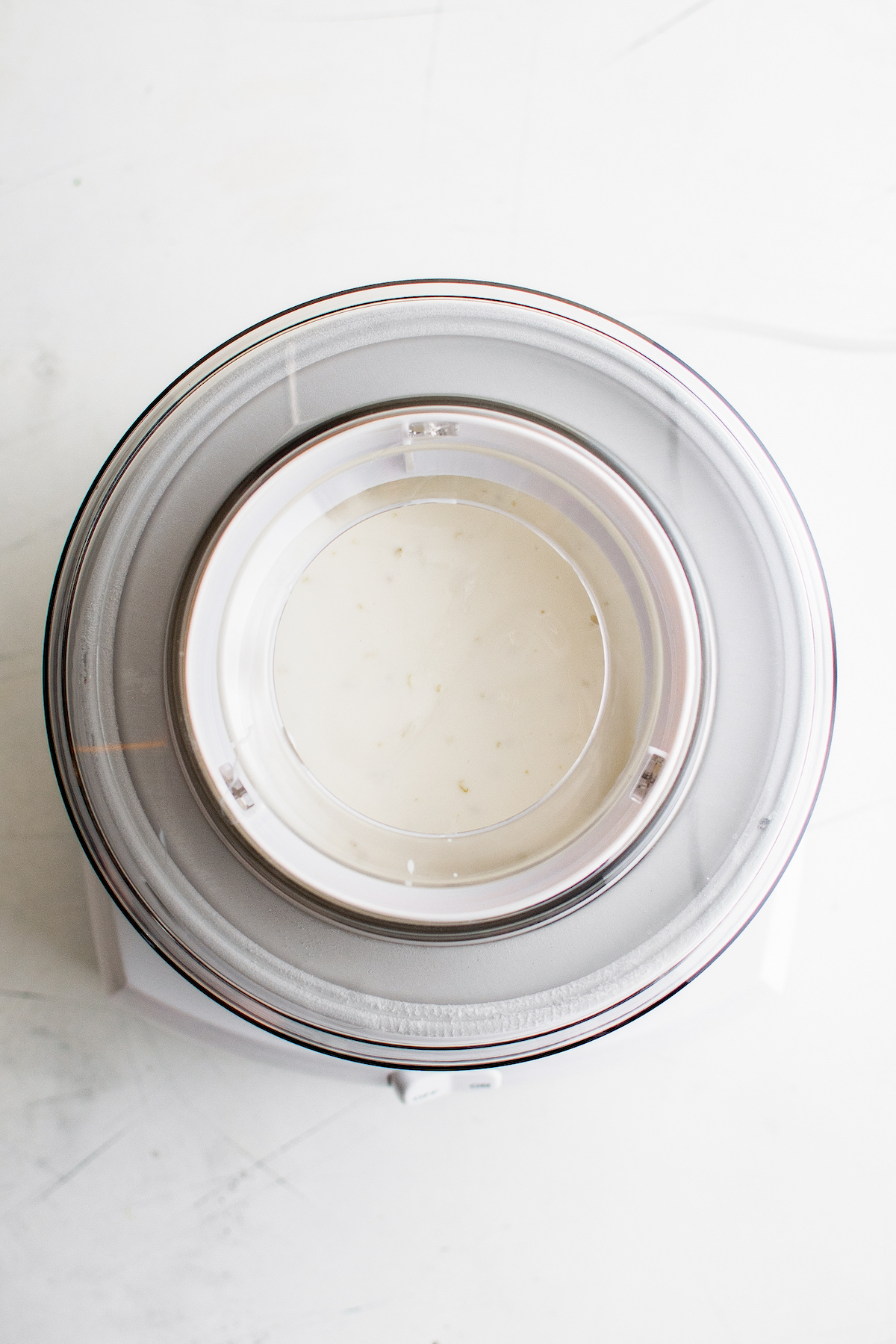 Overhead shot of an ice cream churn filled with frozen yogurt mixture.