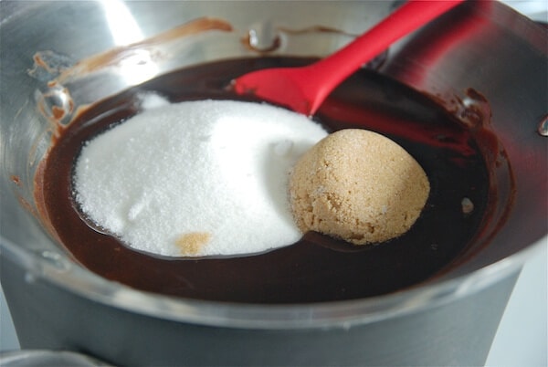 Double boiler filled with melted chocolate, brown sugar and granulated sugar and a red spatula.