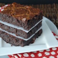 Three brownies stacked on top of each other with a white plate and a red napkin.