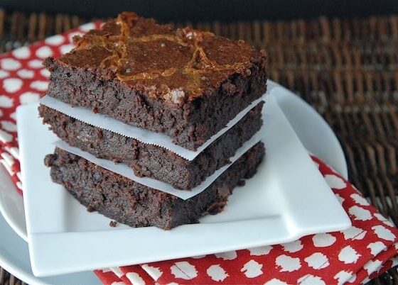 Three brownies stacked on top of each other with a white plate and a red napkin.