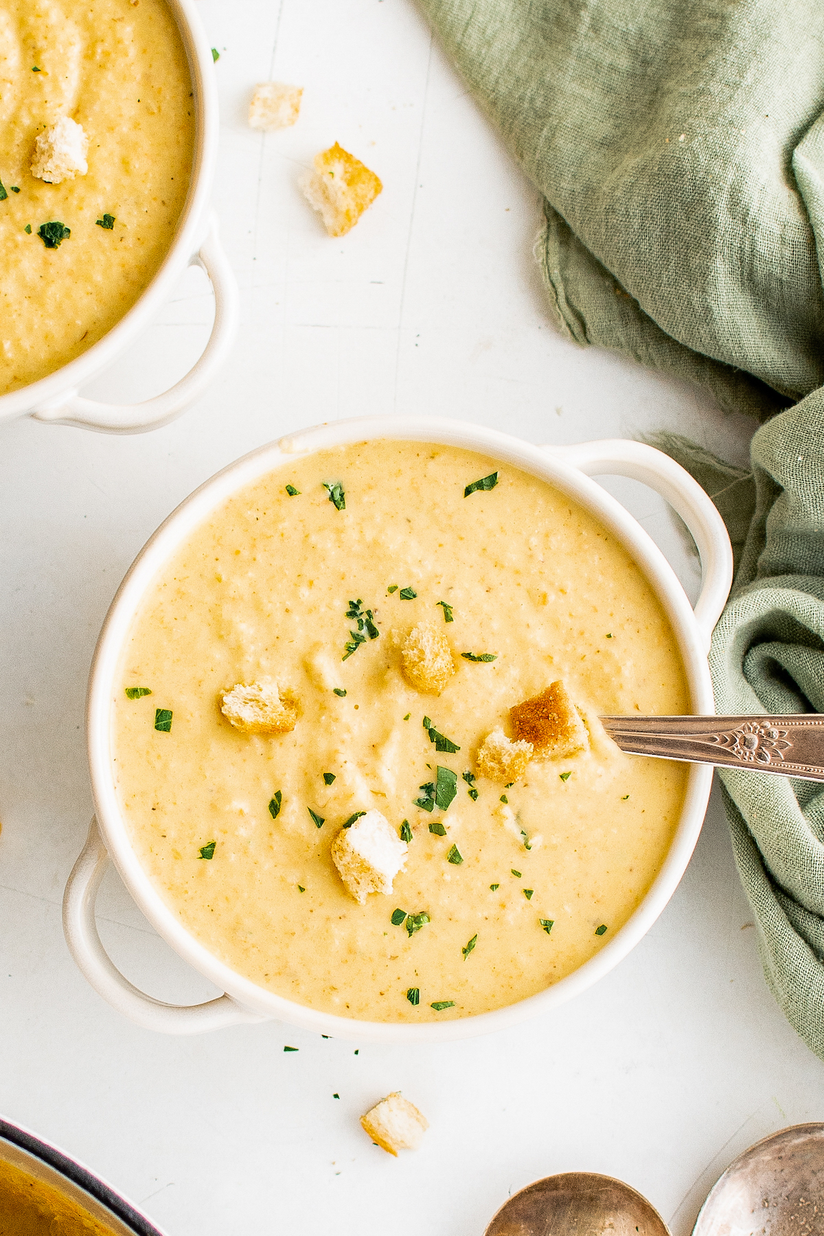 A bowl of creamy soup, topped with croutons and chopped chives.