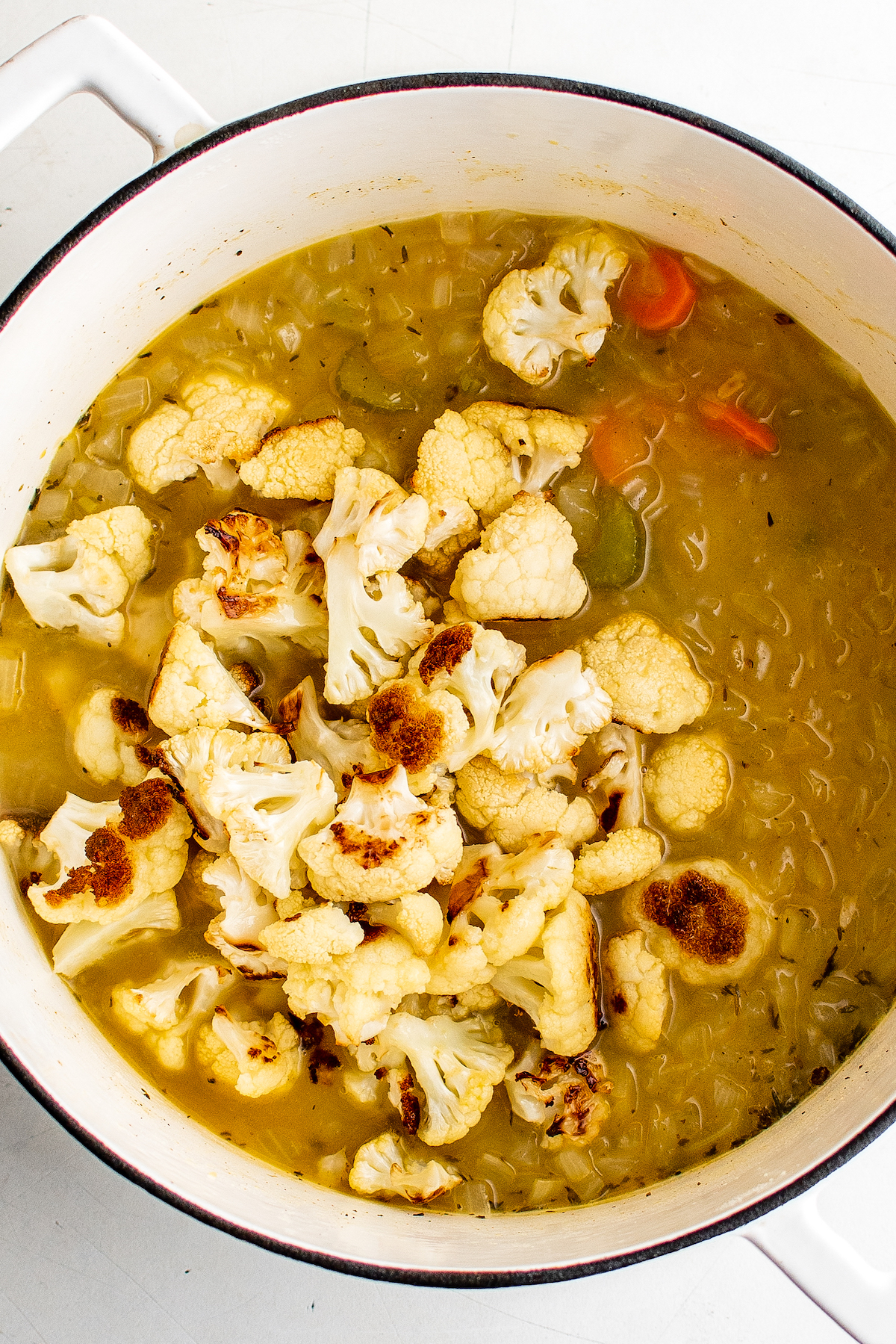 Roasted cauliflower added to a pot of soup.