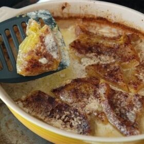 Baked cushaw in a casserole dish with a spatula picking up a slice.