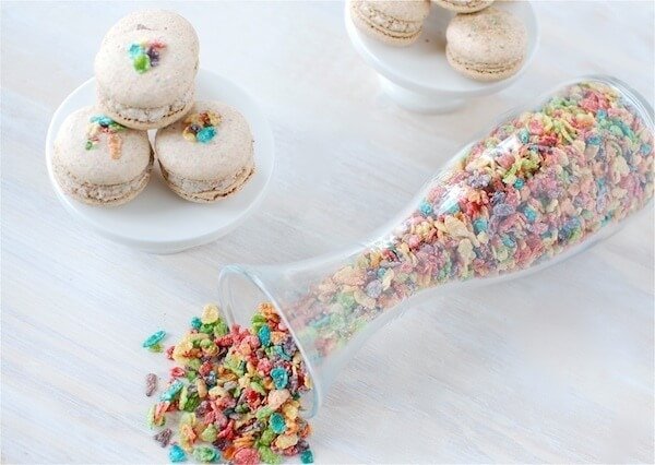 A Plate of Fruity Pebble Macaron Cookies Beside a Spilled Jar of Fruity Pebbles Cereal