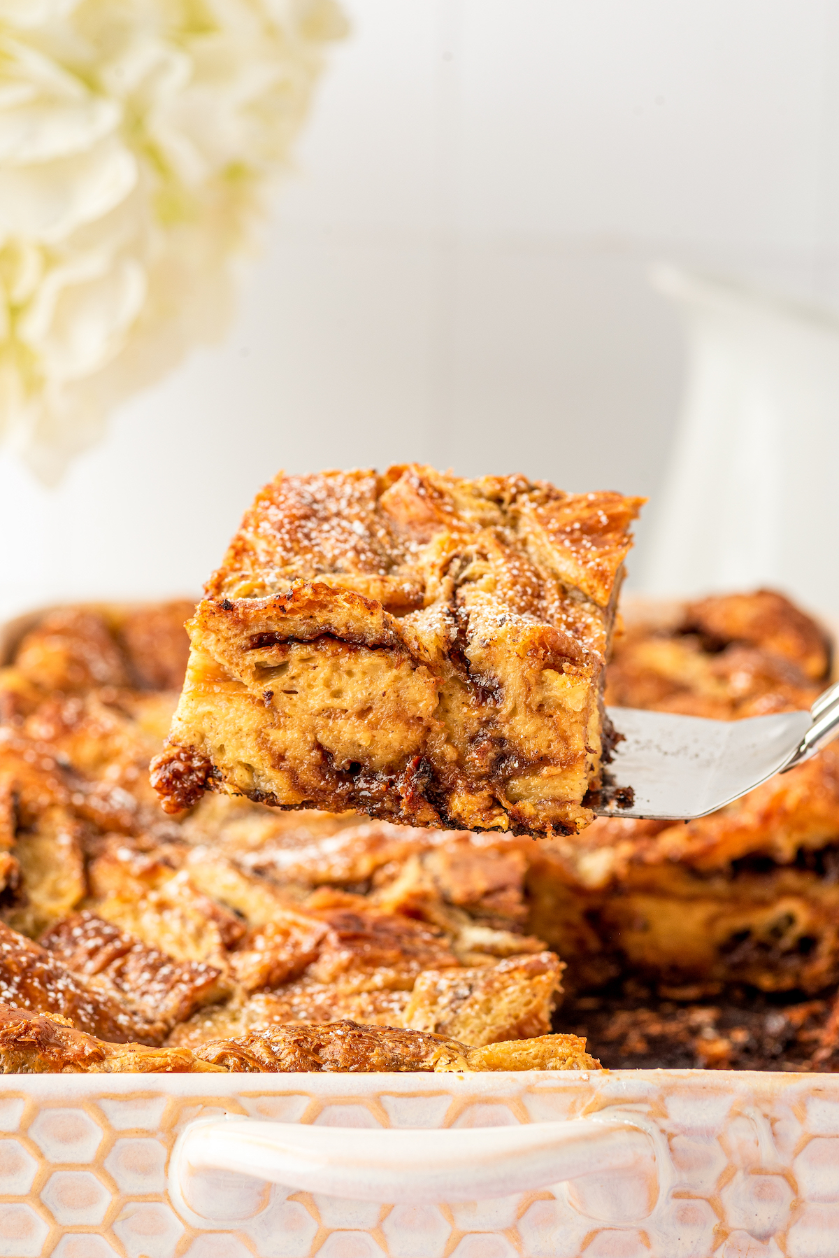 A square of chocolate-hazelnut bread pudding being lifted from a dish.