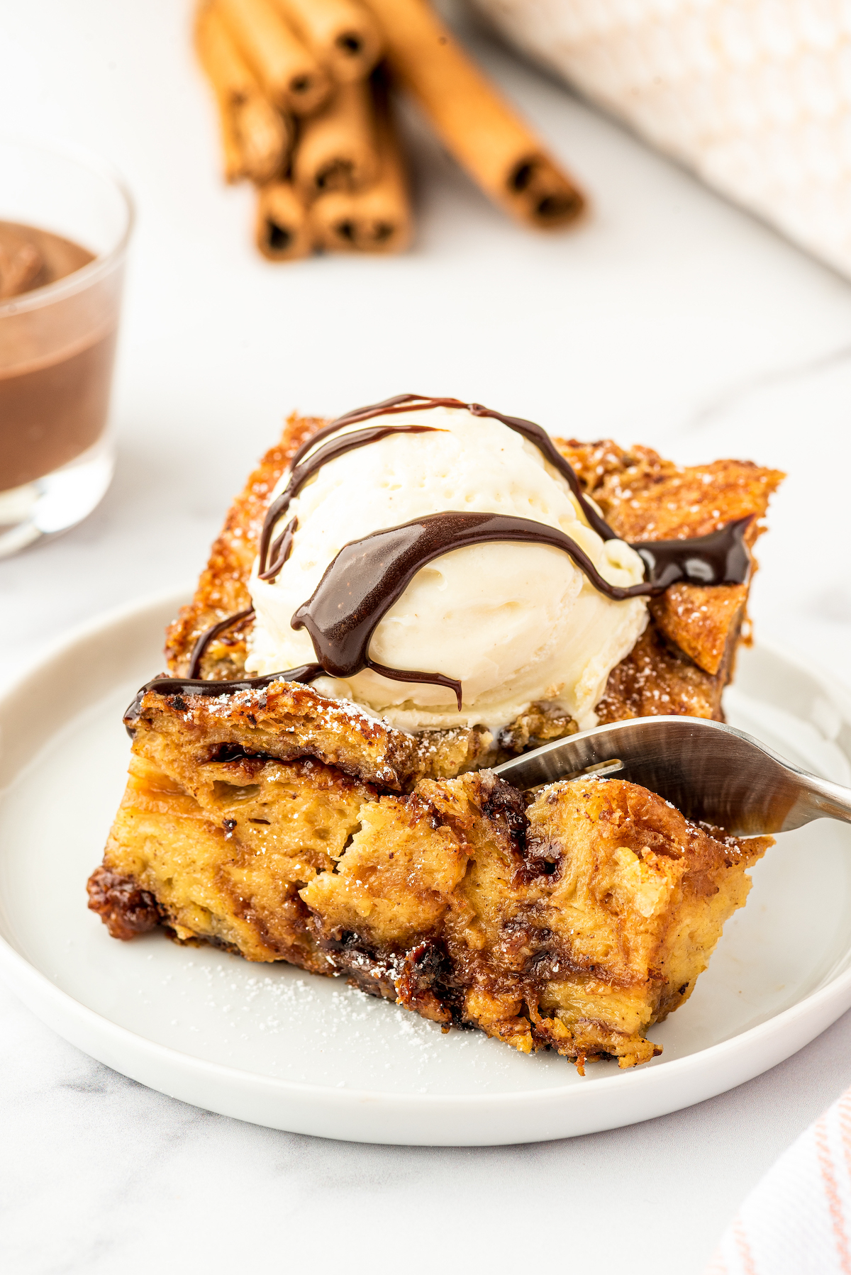 A square of bread pudding with a fork cutting a bite out of it.