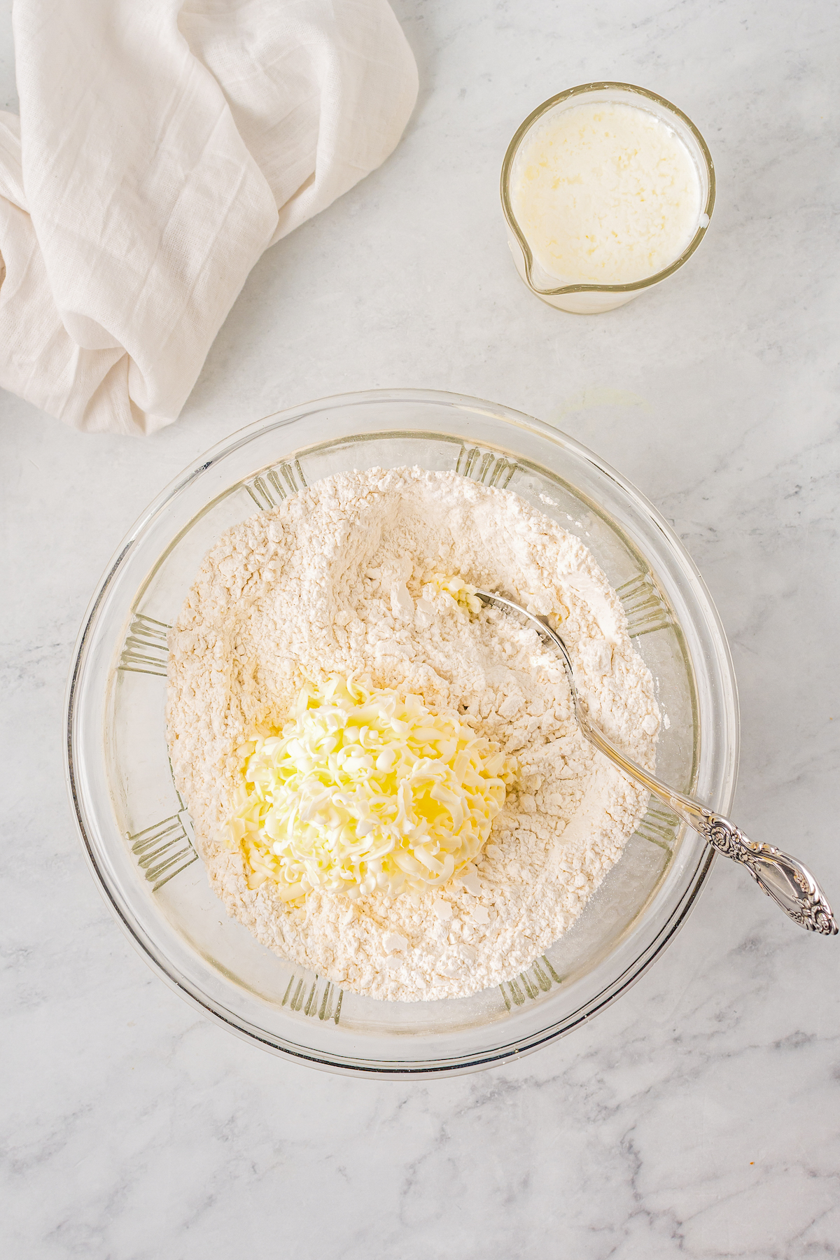 Grated butter and shortening being stirred into dry ingredients.